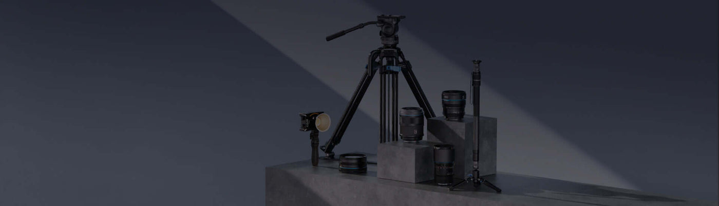 A collection of photography equipment including tripods, lenses, and camera accessories arranged on a gray surface.