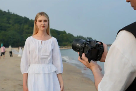 Intermediate photographer capturing a woman in a white dress on the beach with a DSLR camera.