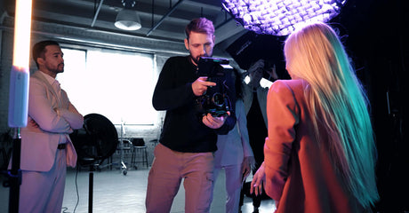 Photographer capturing a model in a studio with professional lighting setup and assistants.