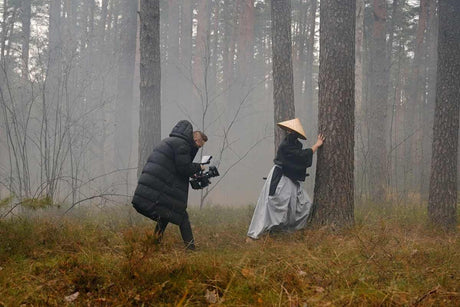 A filmmaker captures a cinematic video scene in a misty forest, exploring techniques for cinematic recording.