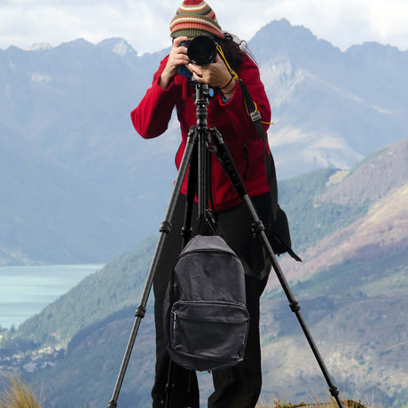 Photographer using a tripod to capture stunning landscape photography in the mountains.