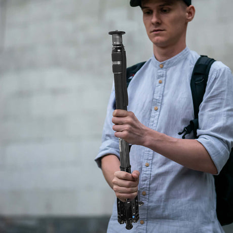 Photographer holding a monopod, showcasing its use in stabilizing camera equipment outdoors.