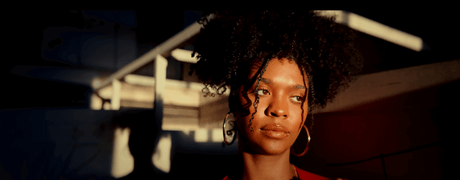 Woman with curly hair in a warm sunset light, showcasing a captivating expression and natural beauty.