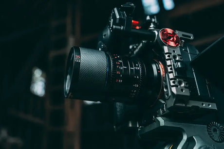 Close-up of a video camera with a detailed lens, showcasing its features and design in a dimly lit environment.