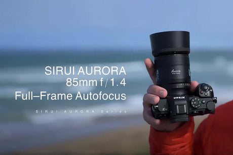 SIRUI AURORA 85mm f/1.4 Full-Frame Autofocus lens being held by a photographer outdoors.