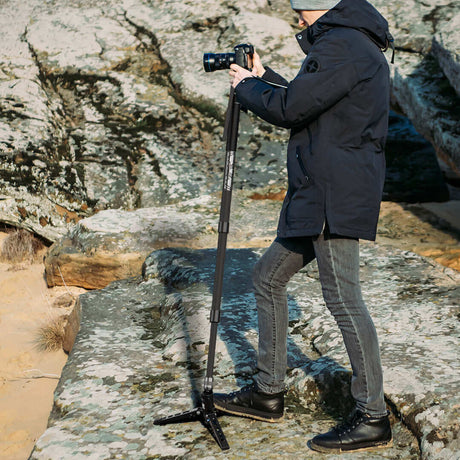 Photographer using a SIRUI tripod on rocky terrain for outdoor photography.