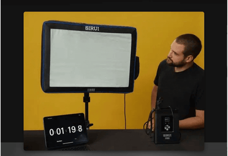 A person demonstrating the SIRUI A100B self-inflating LED light with a timer and power source.