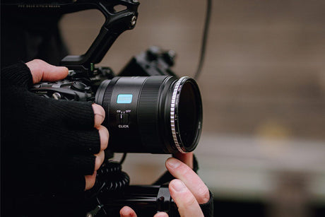 Close-up of a photographer's hands adjusting the lens of a camera with a clear focus on the ISO settings.