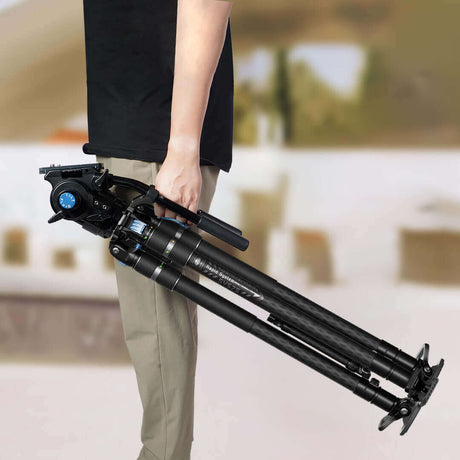 Person holding a compact, folded tripod, showcasing portability for photographers on the go.