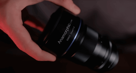 Close-up of a hand holding the SIRUI 50mm f/1.8 anamorphic lens with a sleek black design.