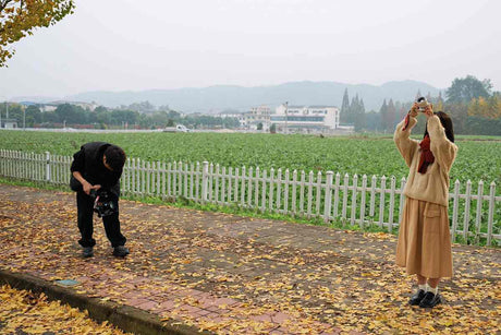 Two photographers capturing images in a foggy outdoor setting with a field in the background.