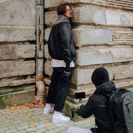 Photographer capturing street style with a camera; model posing against an urban backdrop.