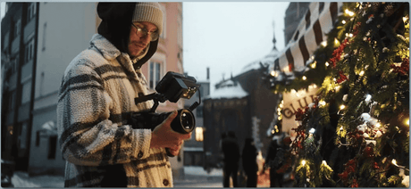 Photographer in a plaid jacket capturing the holiday spirit near a decorated Christmas tree.