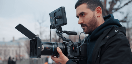 Cinematographer using a professional camera setup, showcasing the Sirui 135mm T2.9 RF lens with a monitor.