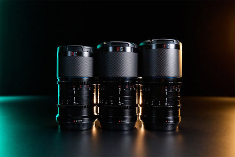 Close-up of three photography lenses with a sleek design, illuminated with creative lighting against a dark background.