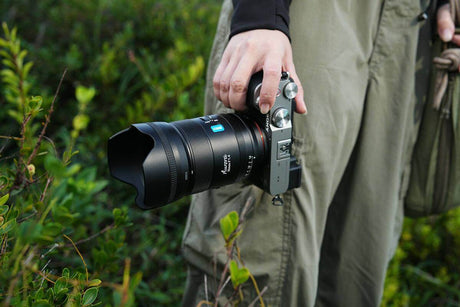 Creator’s Guide: Types of Camera Movements with Examples - a hand holding a camera with a large lens in a natural setting.