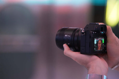Camera with 85mm f/4 lens held in hand, illustrating tips from 'How to Take a Best Photo Every Time: Simple Photography Tricks'