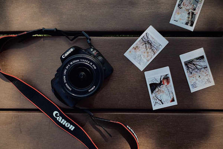 Canon camera with printed photos on wooden surface, representing how to start a photography business with no experience (2025).