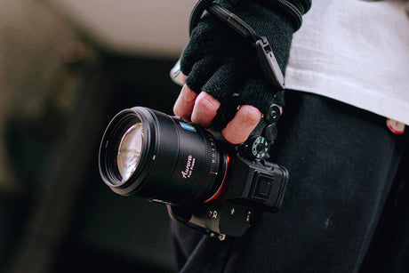 Close-up of a photographer holding a camera with an 85mm lens, showcasing professional photography gear.