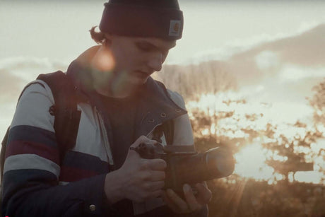 Camera Lens Uses Guide | How to Choose the Right Lens Every Time - Photographer adjusting settings on camera at sunset.