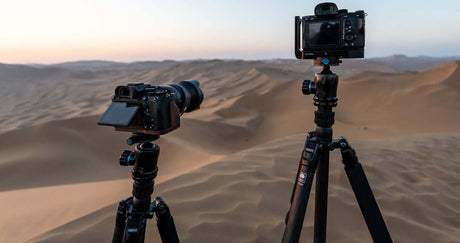 Two cameras mounted on tripods in a desert landscape, demonstrating gear setup for photography.
