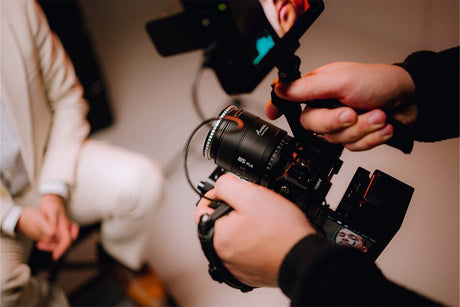 Person holding a camera with a lens, showcasing a compact design during a photo shoot.