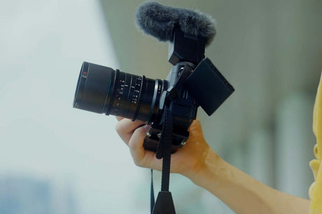 Person holding a camera with a lens and microphone, ideal for capturing black and white headshot photography.